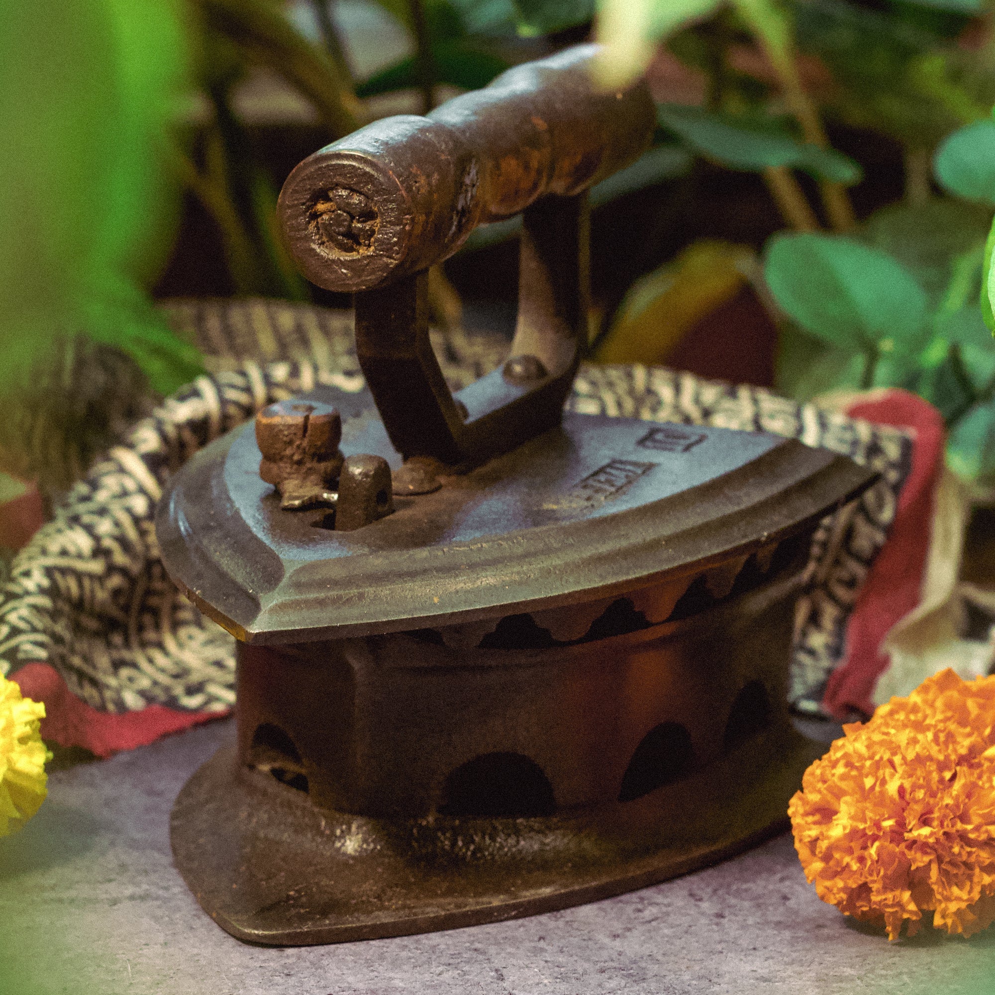 Vintage iron with a rustic appearance on a surface with flowers and fabric in the background