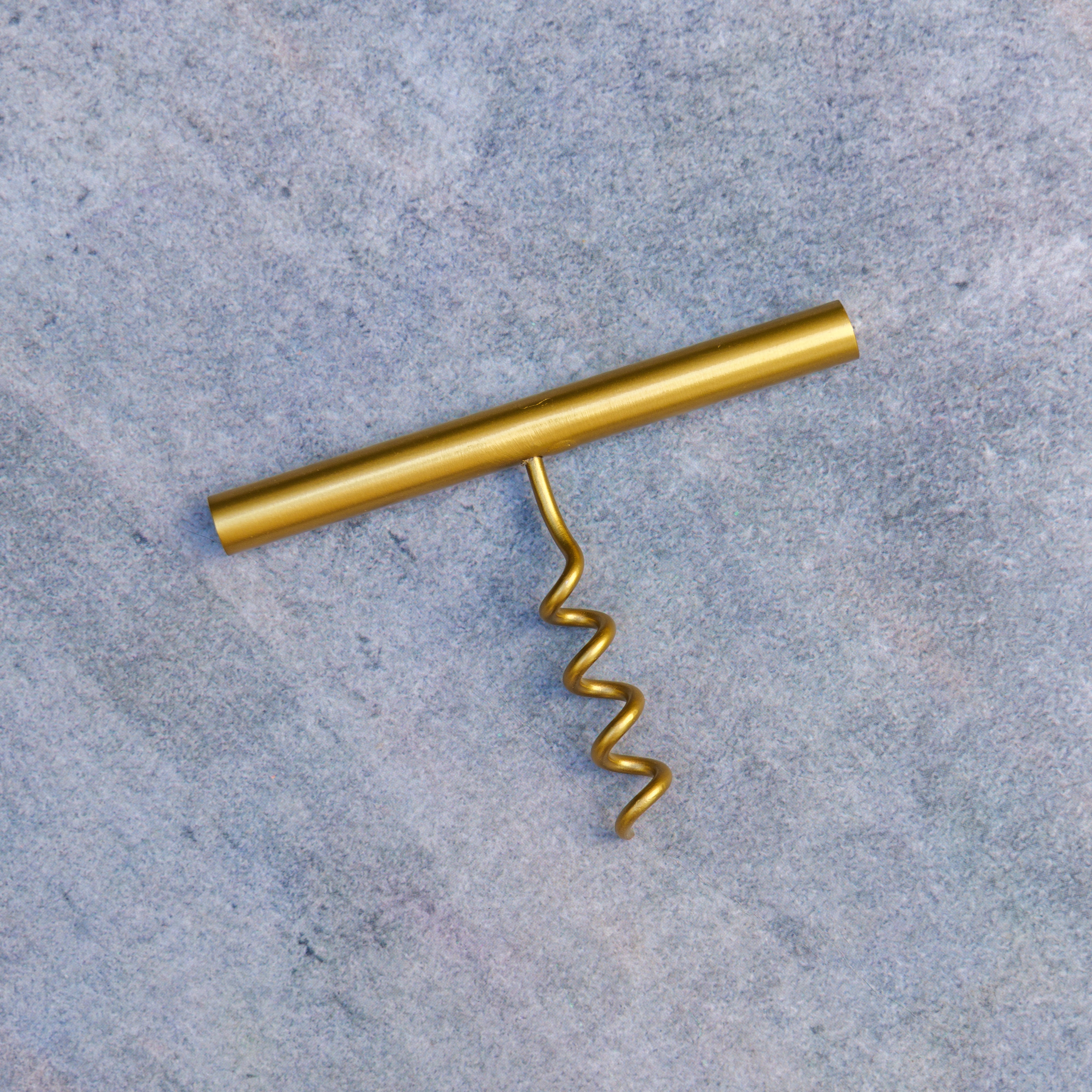 Gold corkscrew on a textured gray surface