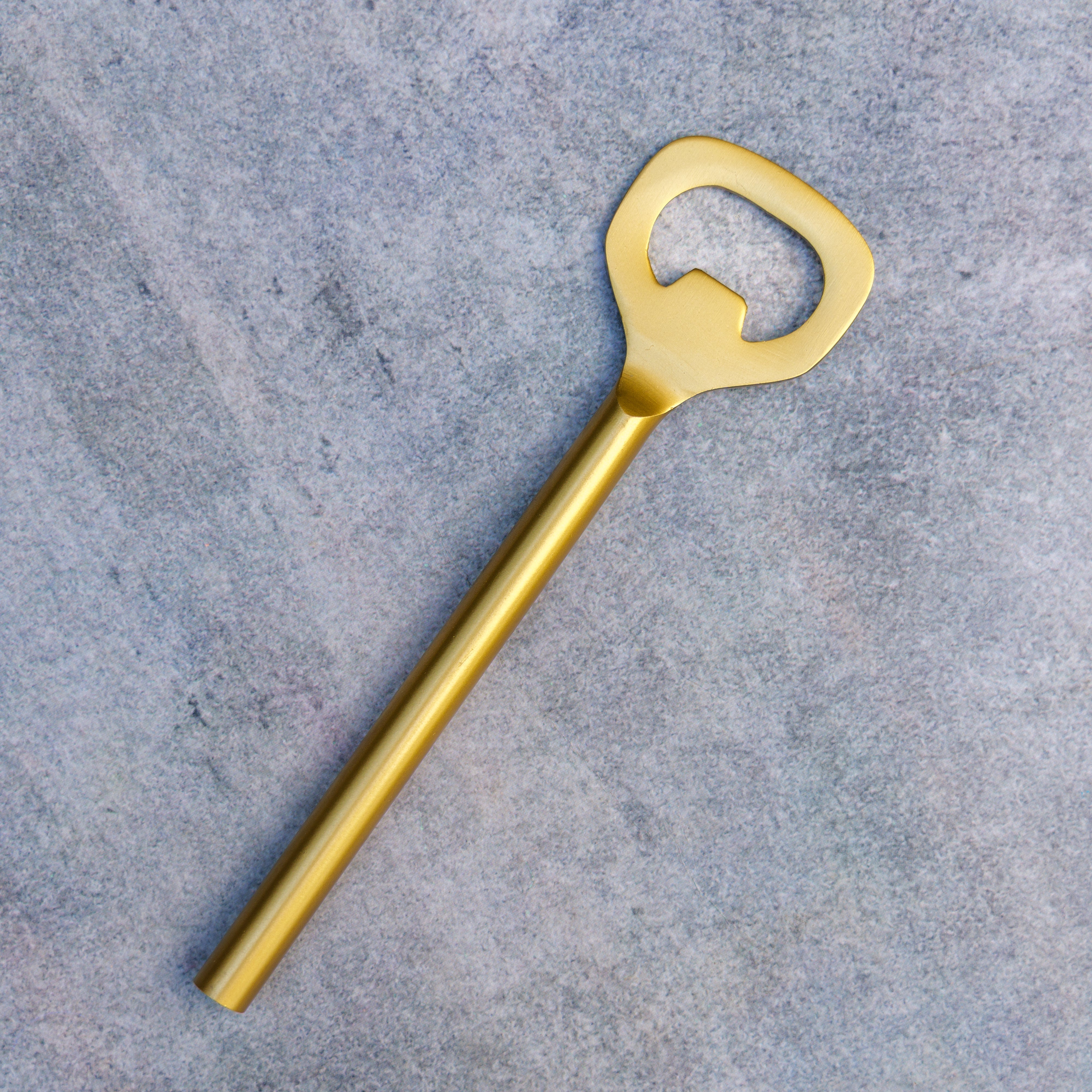 Gold bottle opener on a gray concrete surface