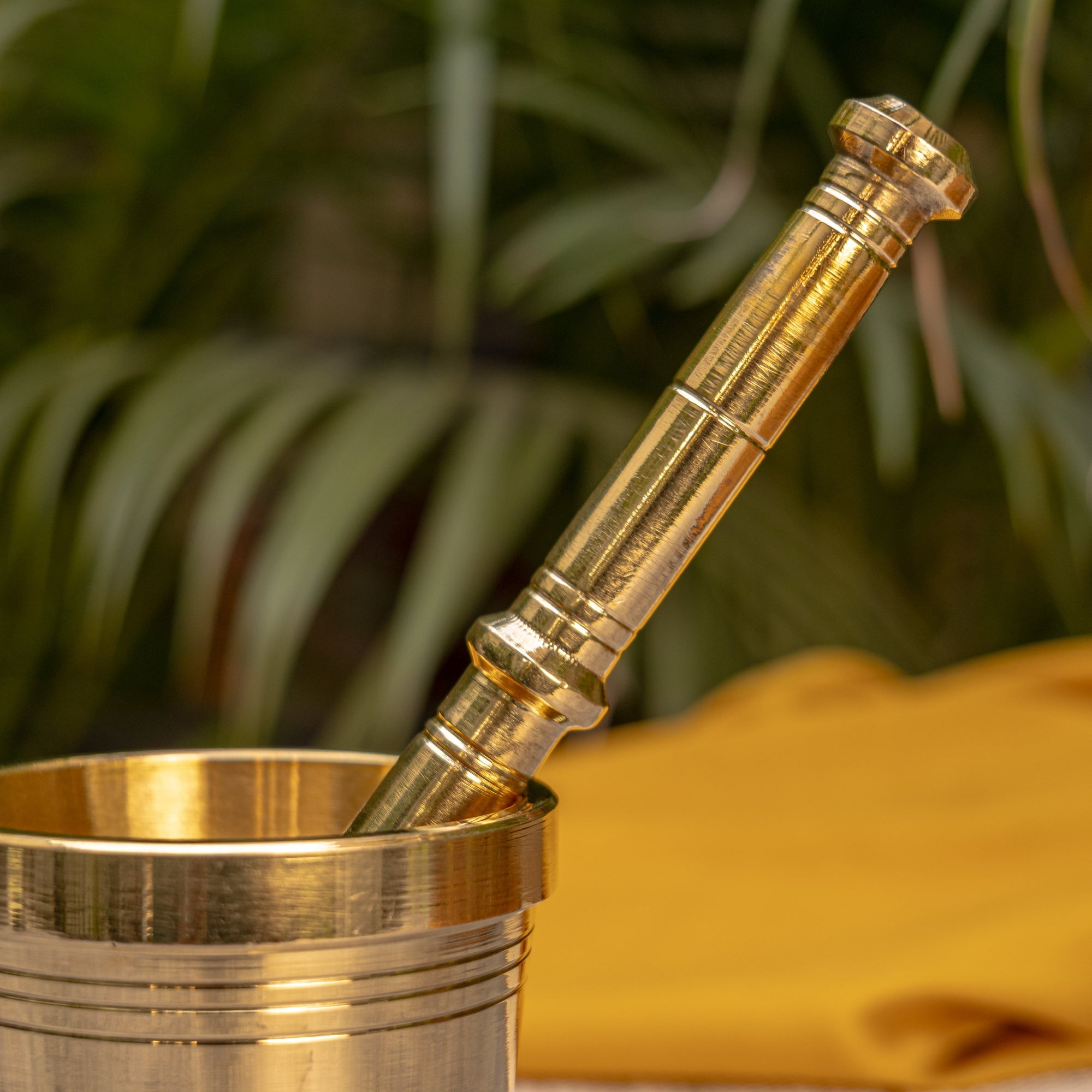 Brass pestle and mortar with a blurred green plant background