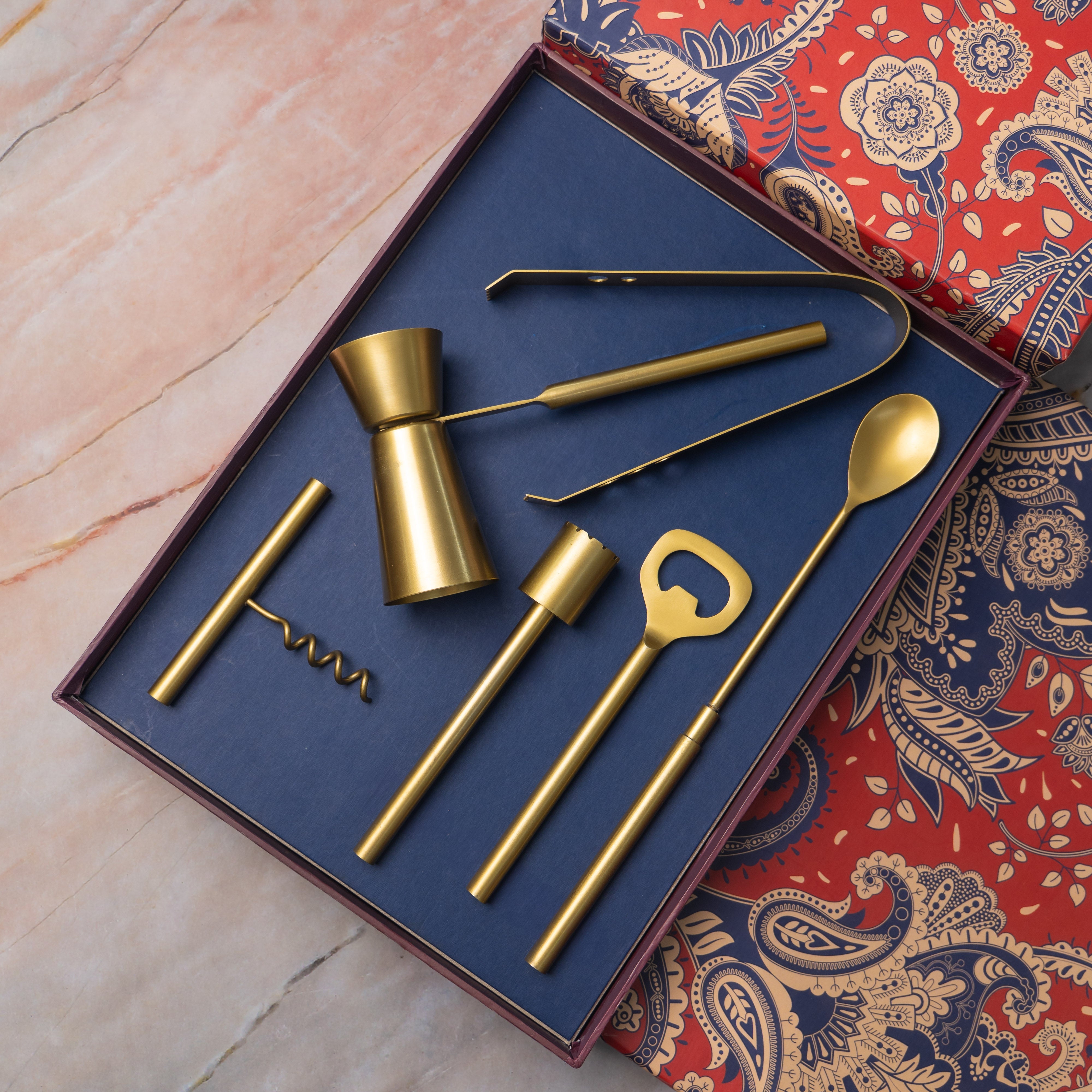 Set of gold bar tools including a jigger, bottle opener, and spoon in a decorative box.