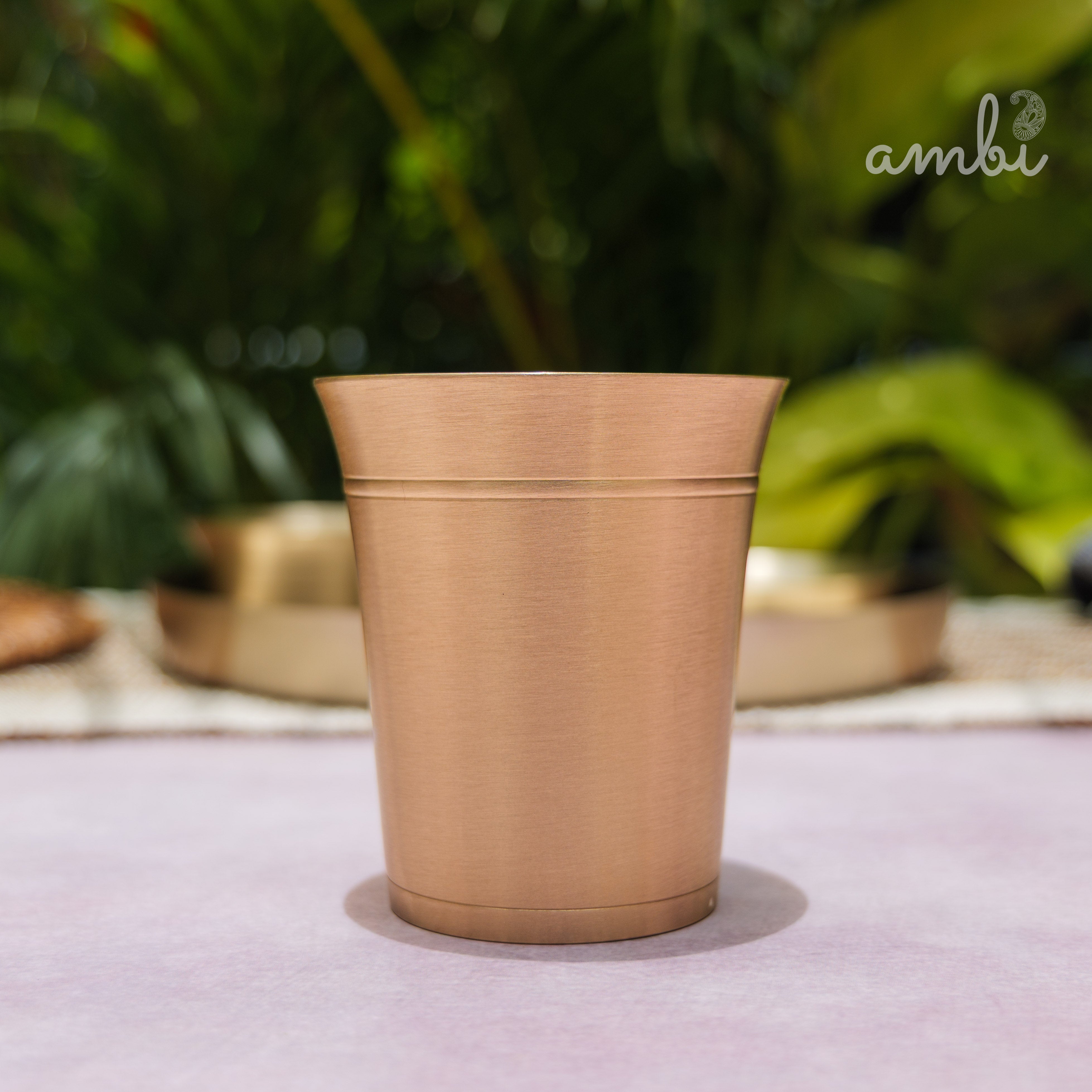 Beige ceramic pot on a light surface with blurred greenery in the background