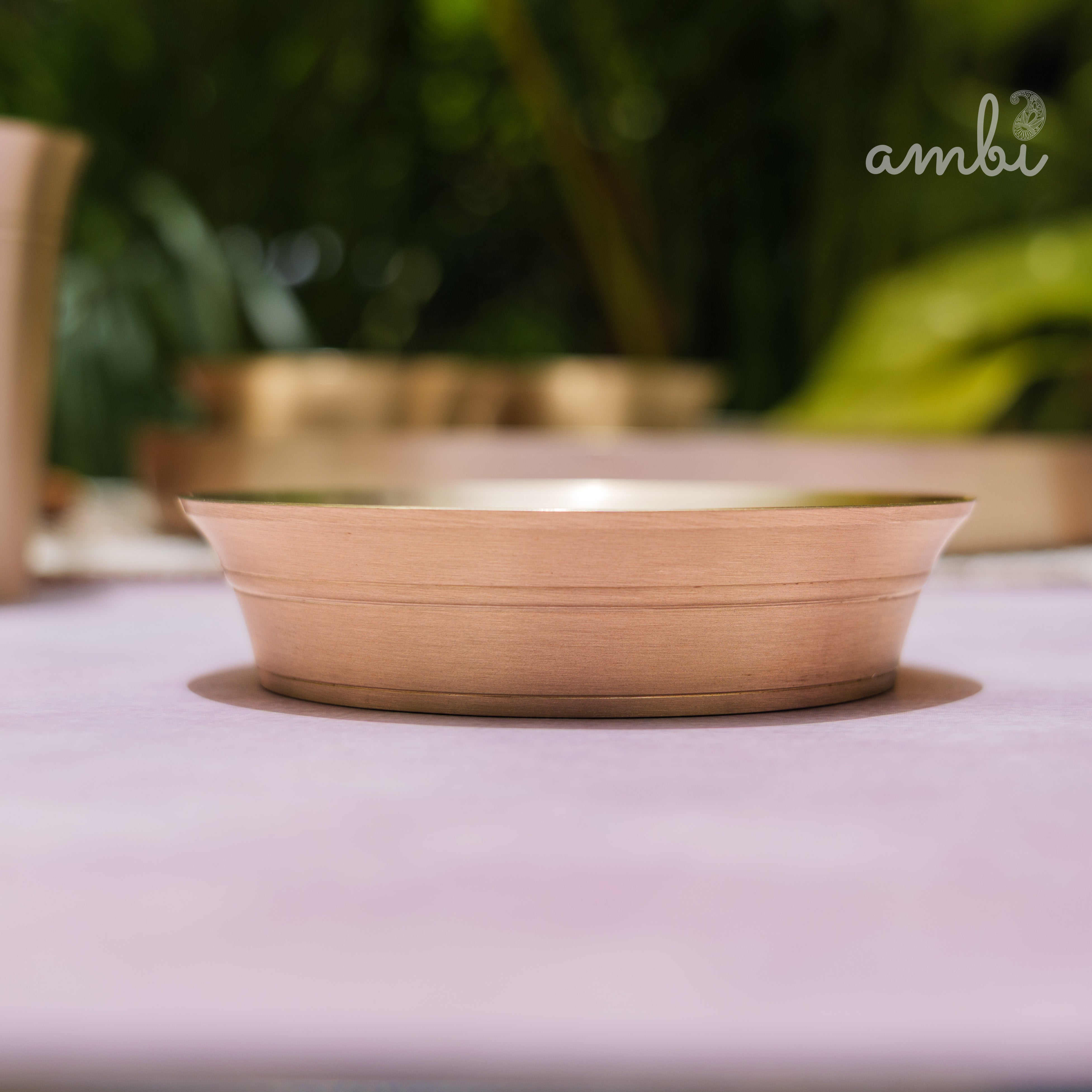 Wooden bowl on a pink surface with blurred greenery in the background