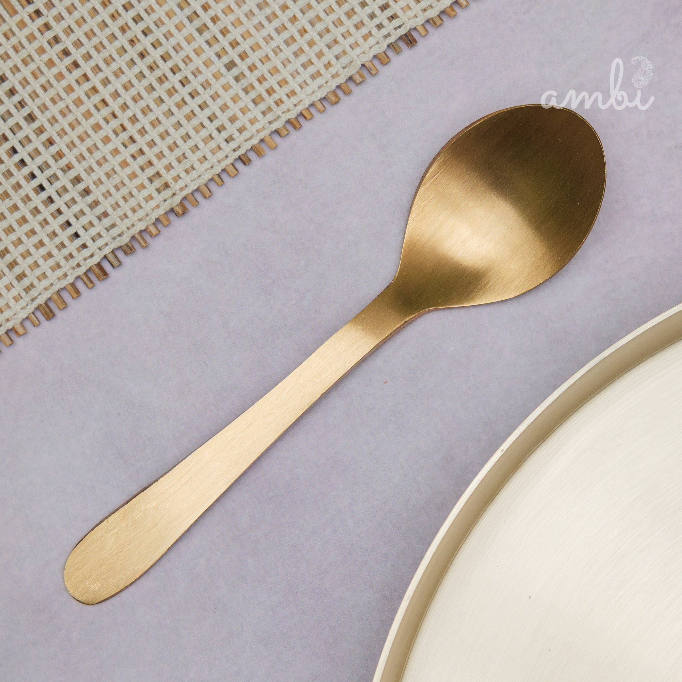 Gold spoon with 'Ambi Home' text on a branded paper background