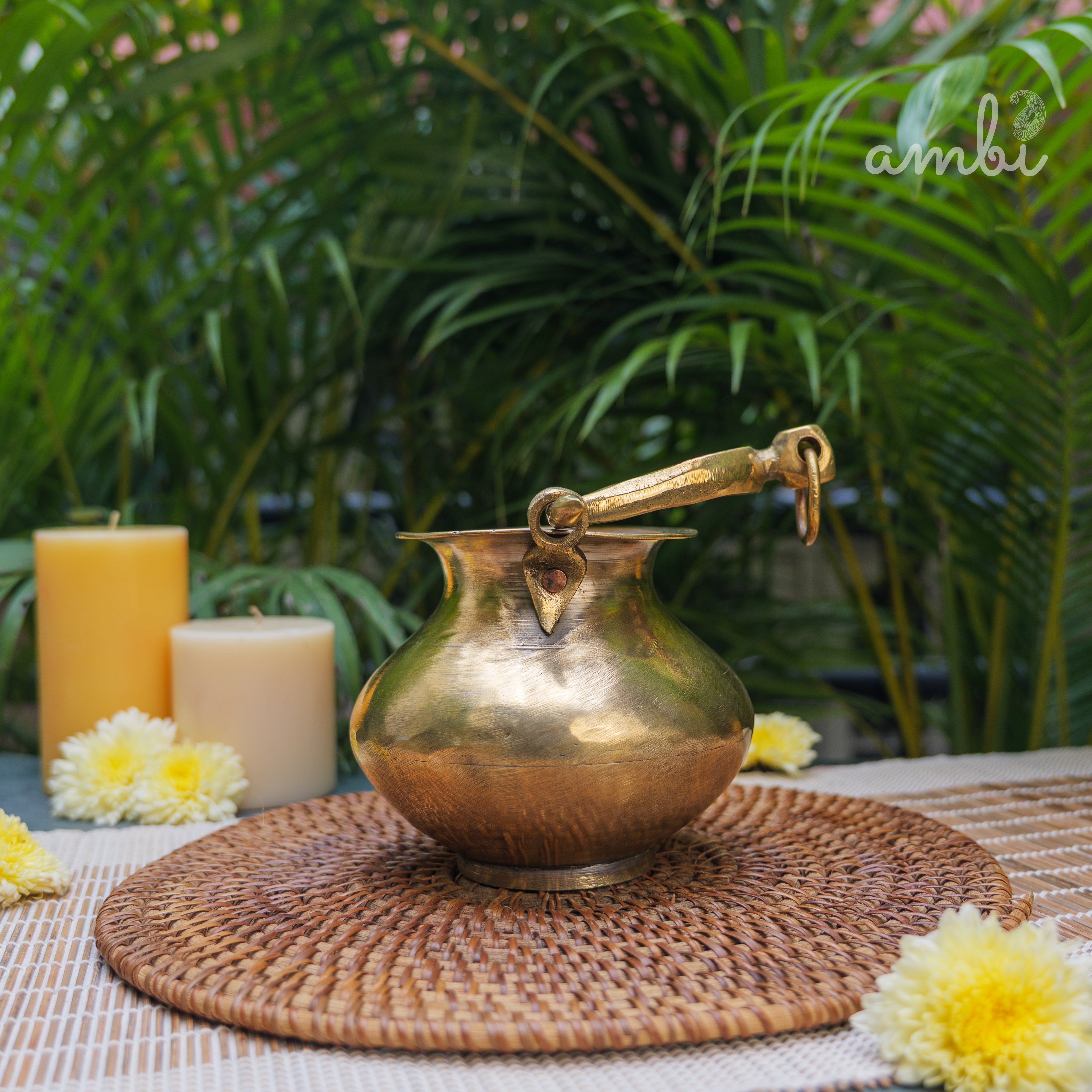 Bronze pitcher on a woven mat with candles and flowers in a garden setting