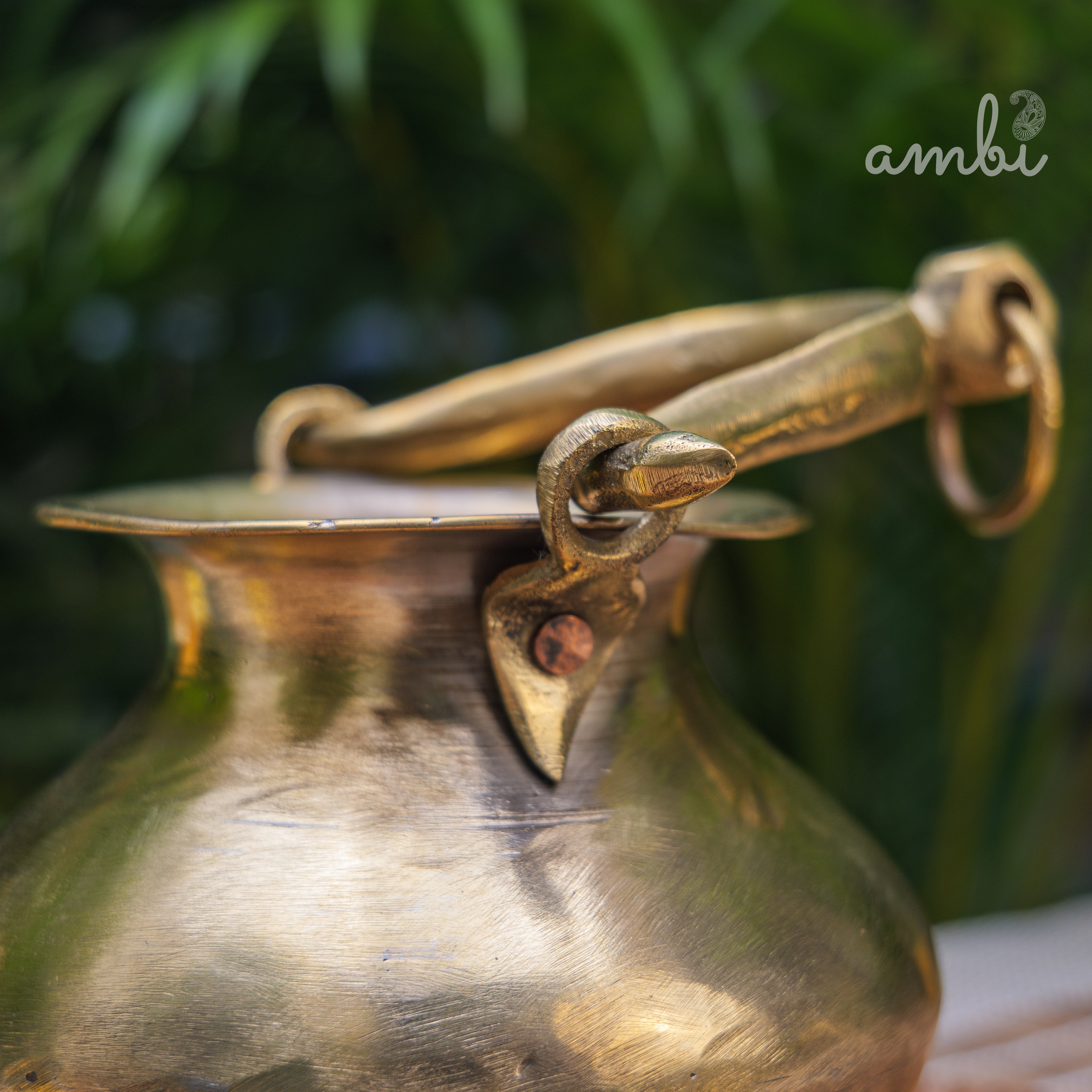 Brass pot with a handle against a blurred green background