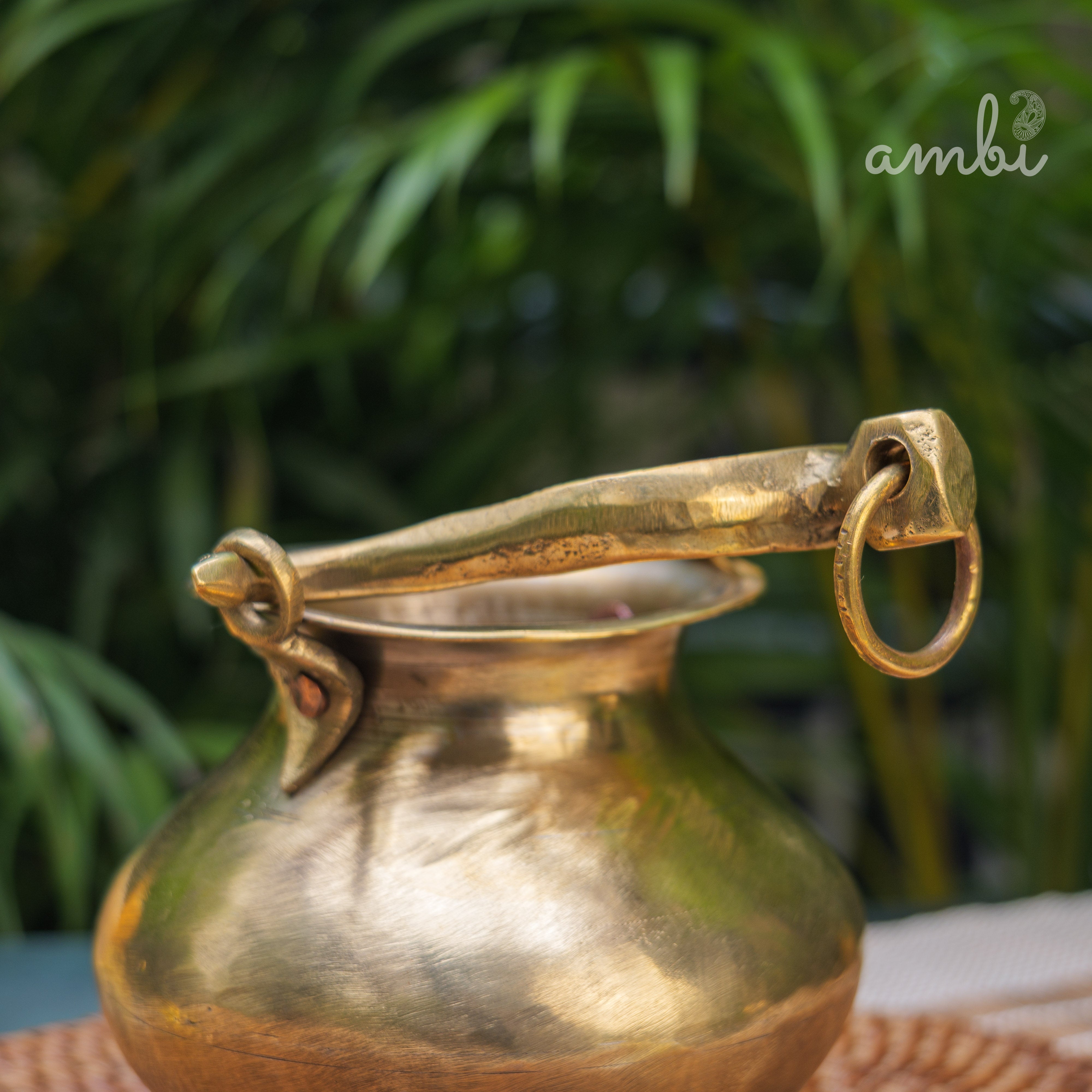 Bronze pitcher with handle on a blurred green background