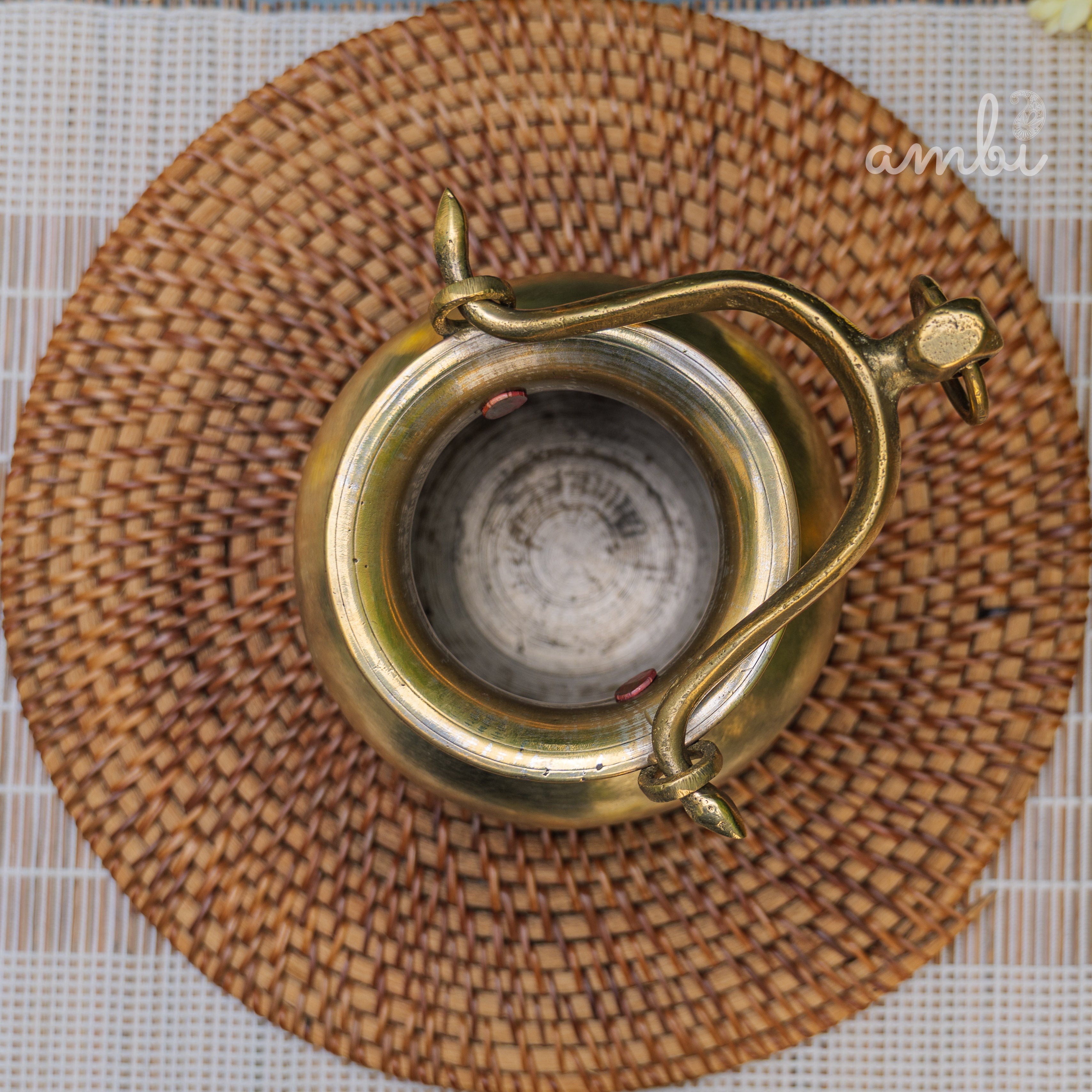 Brass candle holder with decorative design on a woven mat