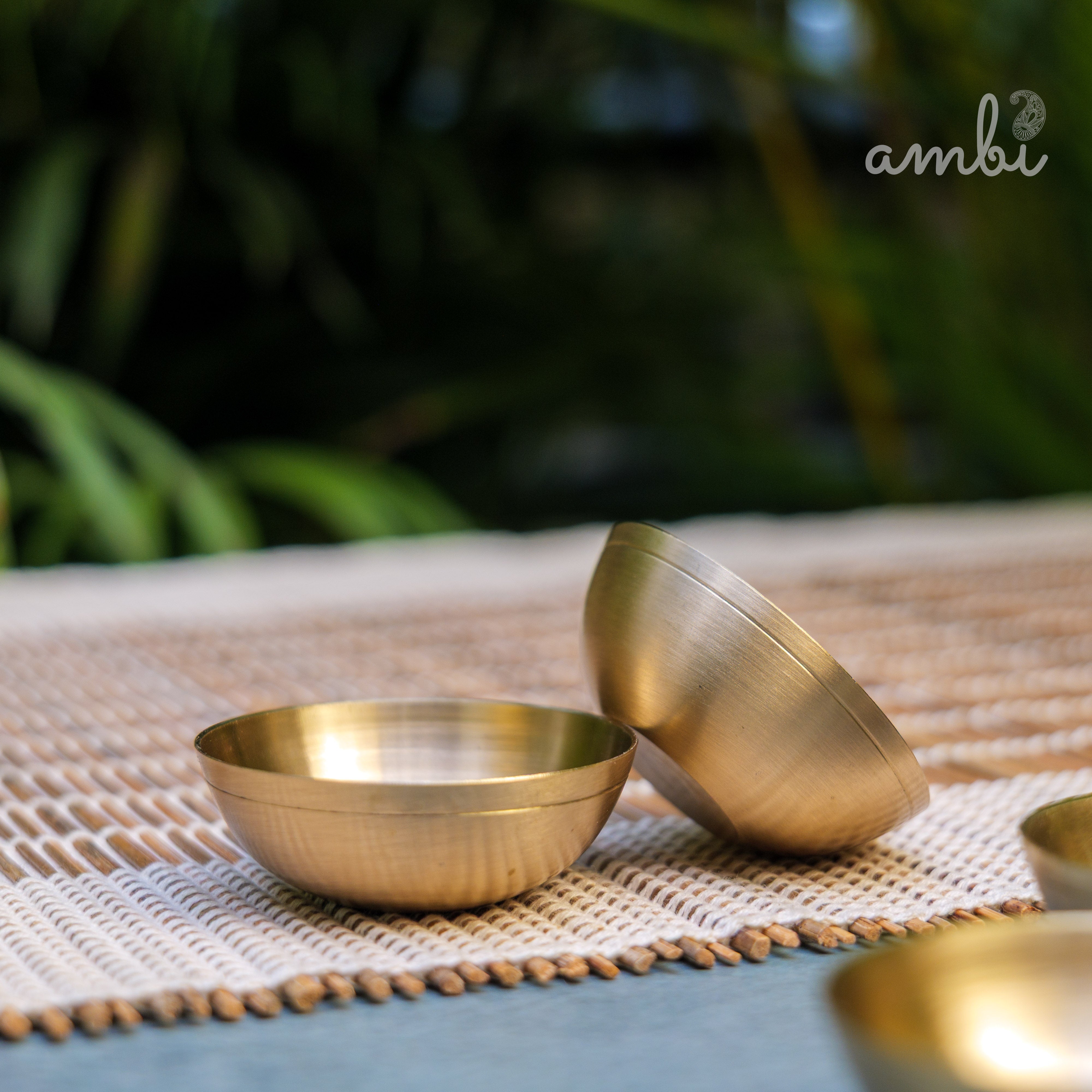 Brass bowls on a woven mat with a blurred natural background