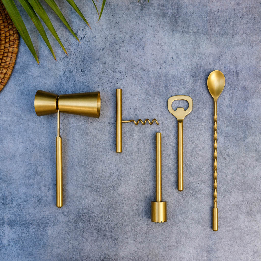 Set of gold bar tools on a textured gray surface with a plant leaf in the corner.